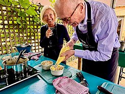 Teilnehmende eines Kochkurses bereiten gemeinsam ein Gericht zu.