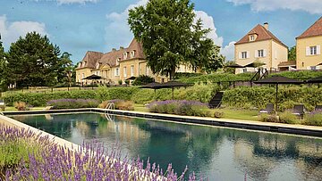 Blick auf Château les Merles: Sandsteingebäude, Garten mit Lavendel und Pool.