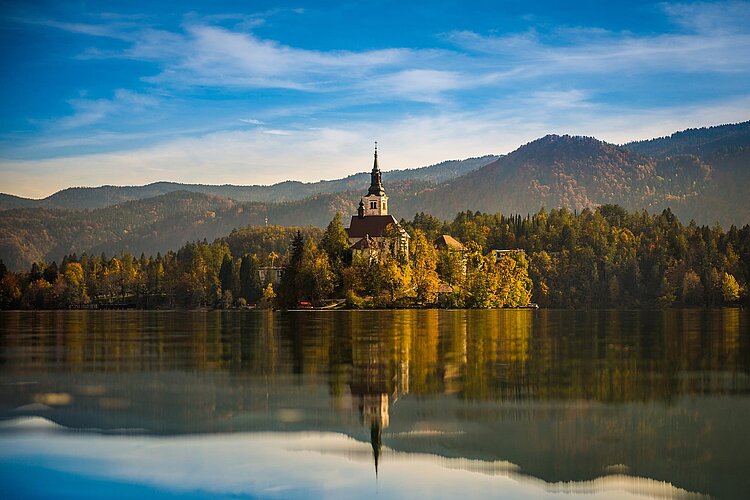 Inselkirche auf dem Bleder See, Herbstfarben, Bergkulisse und Spiegelung.